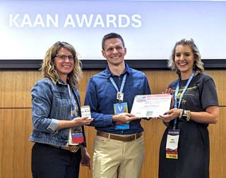 three people on stage during award presentation